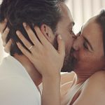 Couple sitting on bed kissing each other