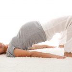 Beautiful pregnant woman doing exercises on the floor