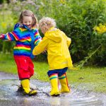 Kids play in rain and puddle in autumn